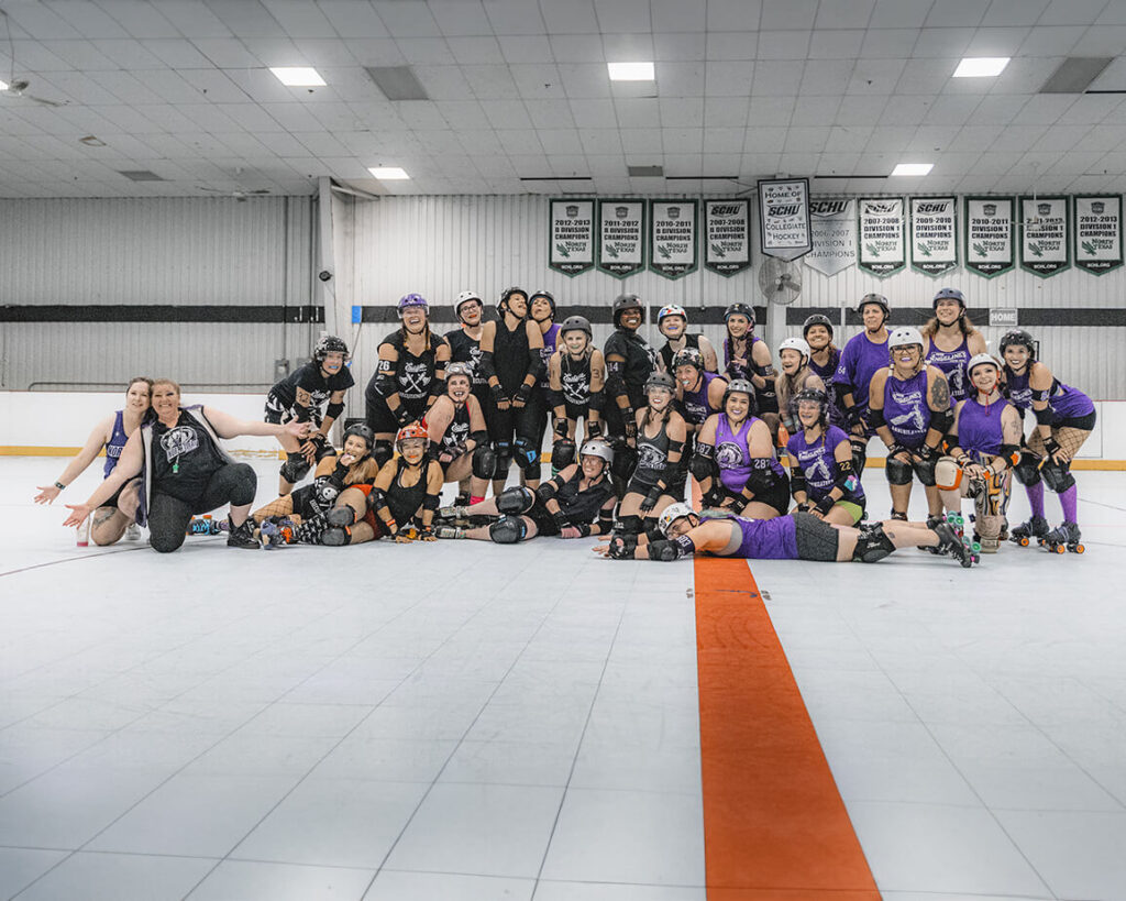 A roller derby team posing on a skating rink after a bout.