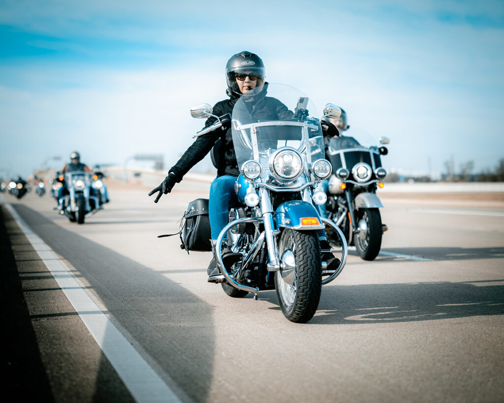 A caucasian woman riding a motorcycle along a highway