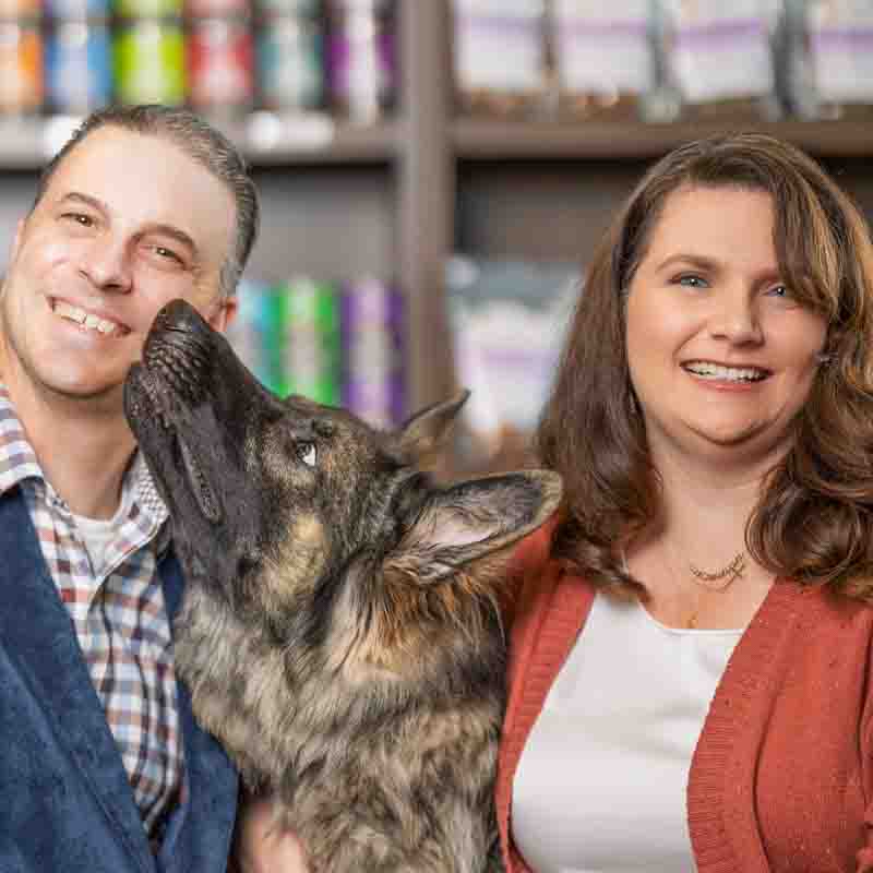 PetWants-Business-Photography-Texas- A man and a woman smiling at the camera with a dog sitting between the.