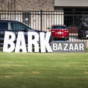 PetWants-Business-Photography-Texas-3- Two signs against a fence of a grass field that spell out Bark Bazaar.
