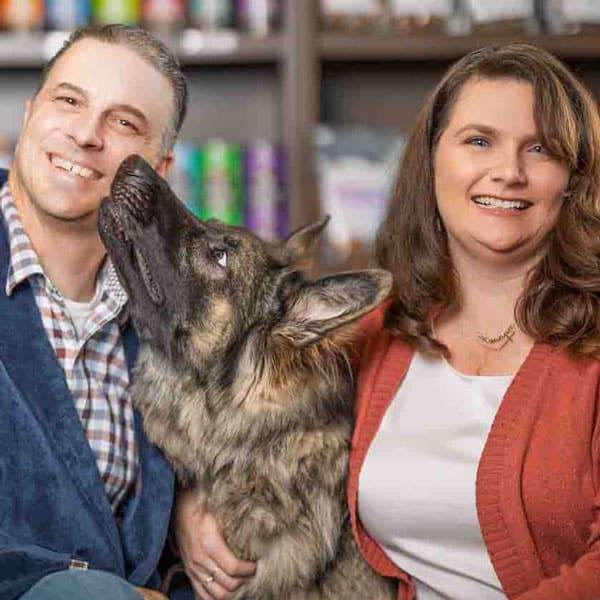PetWants-Roanoke-Leadership-Photo A causcian male and female looking at the camera and smiling with a German shepherd dog sitting between them.