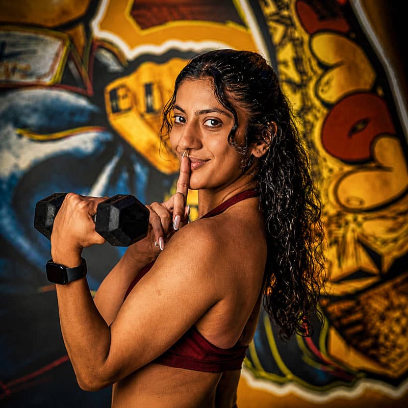fitness-photography-portraits-dallas a southwest asian woman holing a dumbbell and pressing a finger to her lips.
