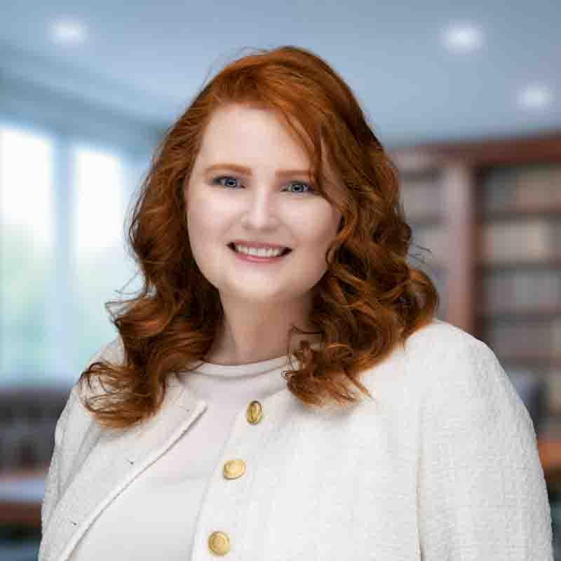 red head caucasian female wearing a white blouse and white cardigan