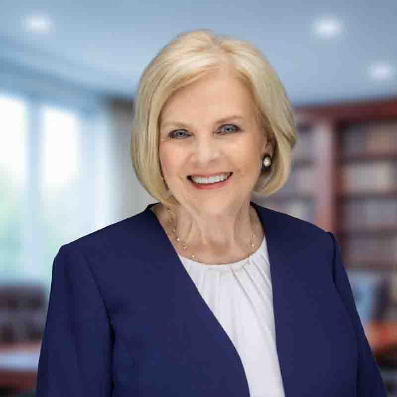 blonde caucasian female wearing a blue suit jacket and white blouse.