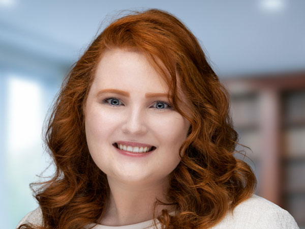 hogue-barnett-headshot-landscape-payton-frisco-texas caucasian female with red hair in a white top smiling at the camera