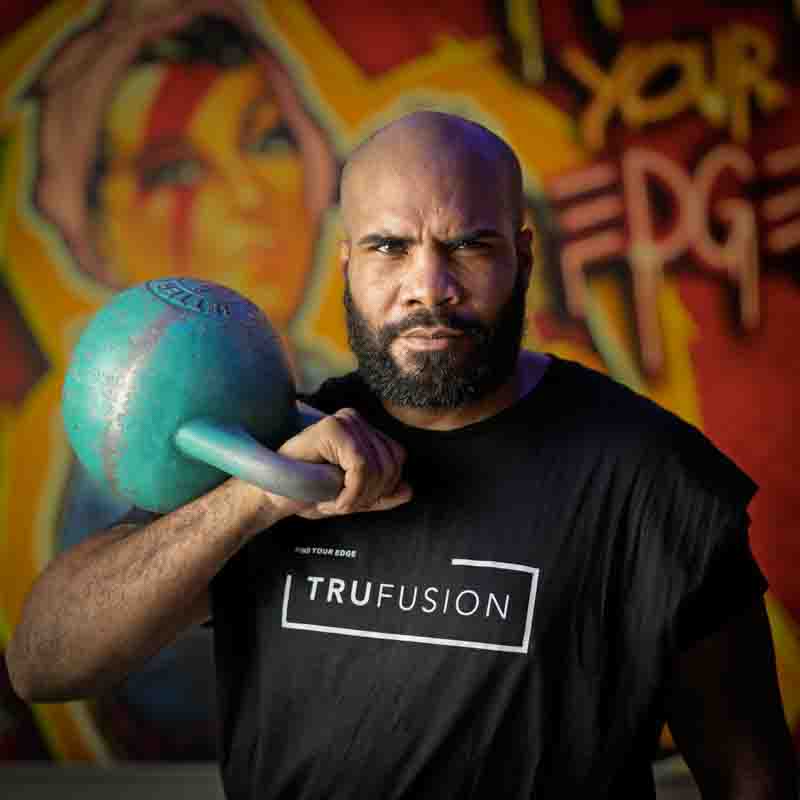 a black male wearing a black t-shirt and holding a turquoise dumbbell on his right shoulder