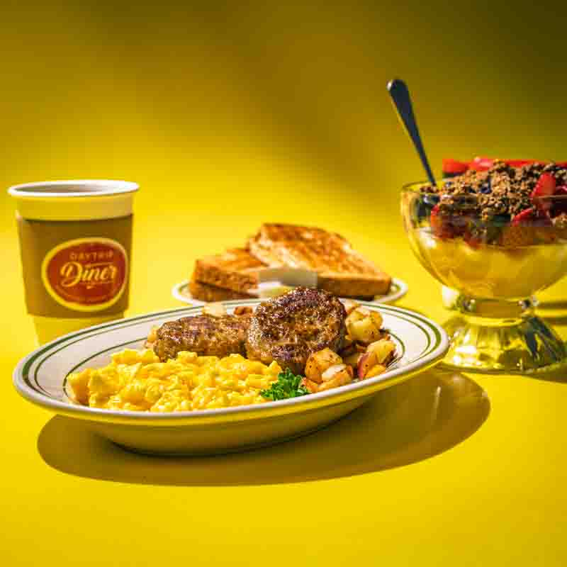 restaurant-breakfast-daytrip-diner-grapevine-texas a plate of scrambled eggs served with sausage patties and diced potatoes